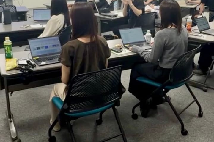 企業研修の会場。受講者がノートパソコンを開いて作業している後ろ姿